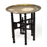 A Persian style brass tray table, the charger engraved with Egyptian figures,