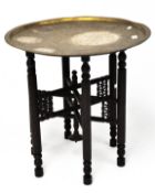 A Persian style brass tray table, the charger engraved with Egyptian figures,