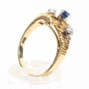A yellow metal ring with bark texture finish and set with a central sapphire and two diamonds