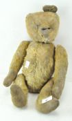 A vintage teddy bear, golden fur and felt paws, eyes and one ear missing,