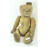 A vintage teddy bear, golden fur and felt paws, eyes and one ear missing,