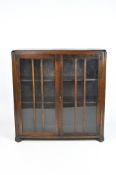 An Art Deco oak bookcase with fluted cut corners, with two shelves behind glazed doors,