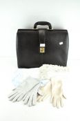 A vintage 'Collezione' black leather case with two pairs of ladies gloves and two tablecloths