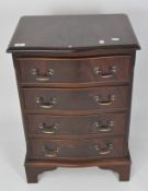 A reproduction serpentine front chest of drawers, covered in mahogany veneer,