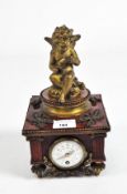 An early 20th century mantel clock with an enamel dial in a wooden faux marble case,