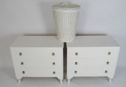 A pair of white painted chests of drawers and a wicker basket, each chest with three long drawers,