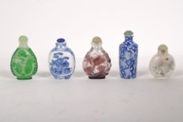 Five Oriental snuff bottles, two blue and white ceramic examples with floral decoration,