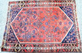 A red ground rug with blue, green and brown patterns,