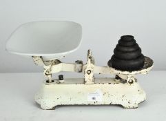 A set of vintage scales, the white metal frame supporting an enamel dish and a set of five weights,