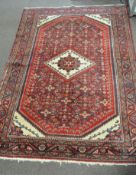 A Hamadan Persian rug woven in red, cream and blue with lozenges and geometric ornament,