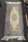 A small Chinese rug, 20th century, woven with flowers on ivory cream ground,