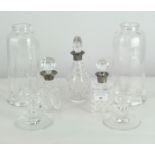 A group of three cut glass bottles with glass storm lanterns and a pair of glass candlestick bases