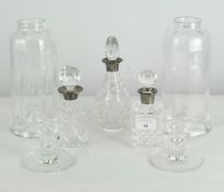 A group of three cut glass bottles with glass storm lanterns and a pair of glass candlestick bases