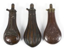 Three 19th century copper and brass powder flasks, one cast with pheasants in a cartouche,