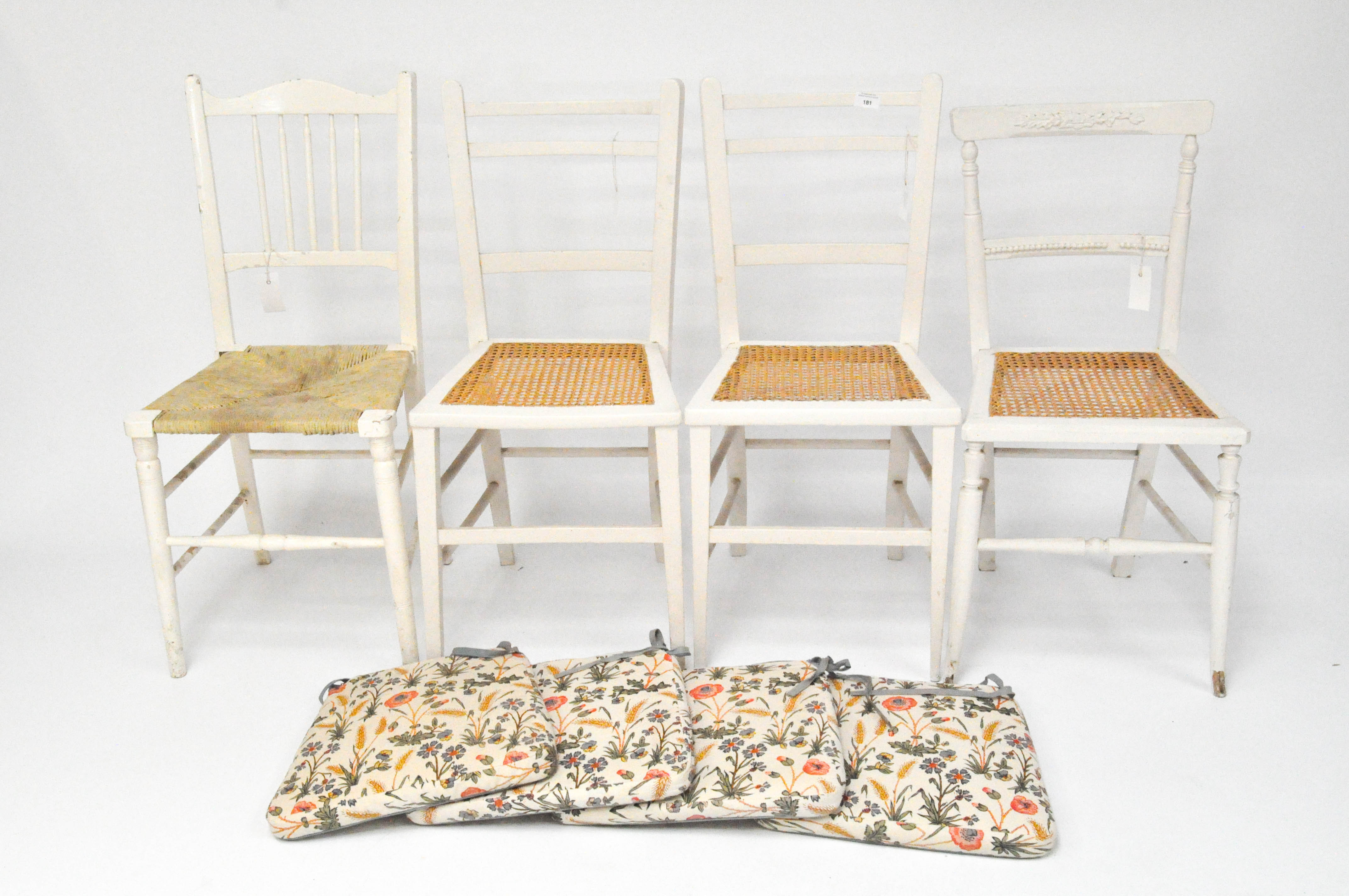 Four vintage painted white chairs, three with wicker seats,