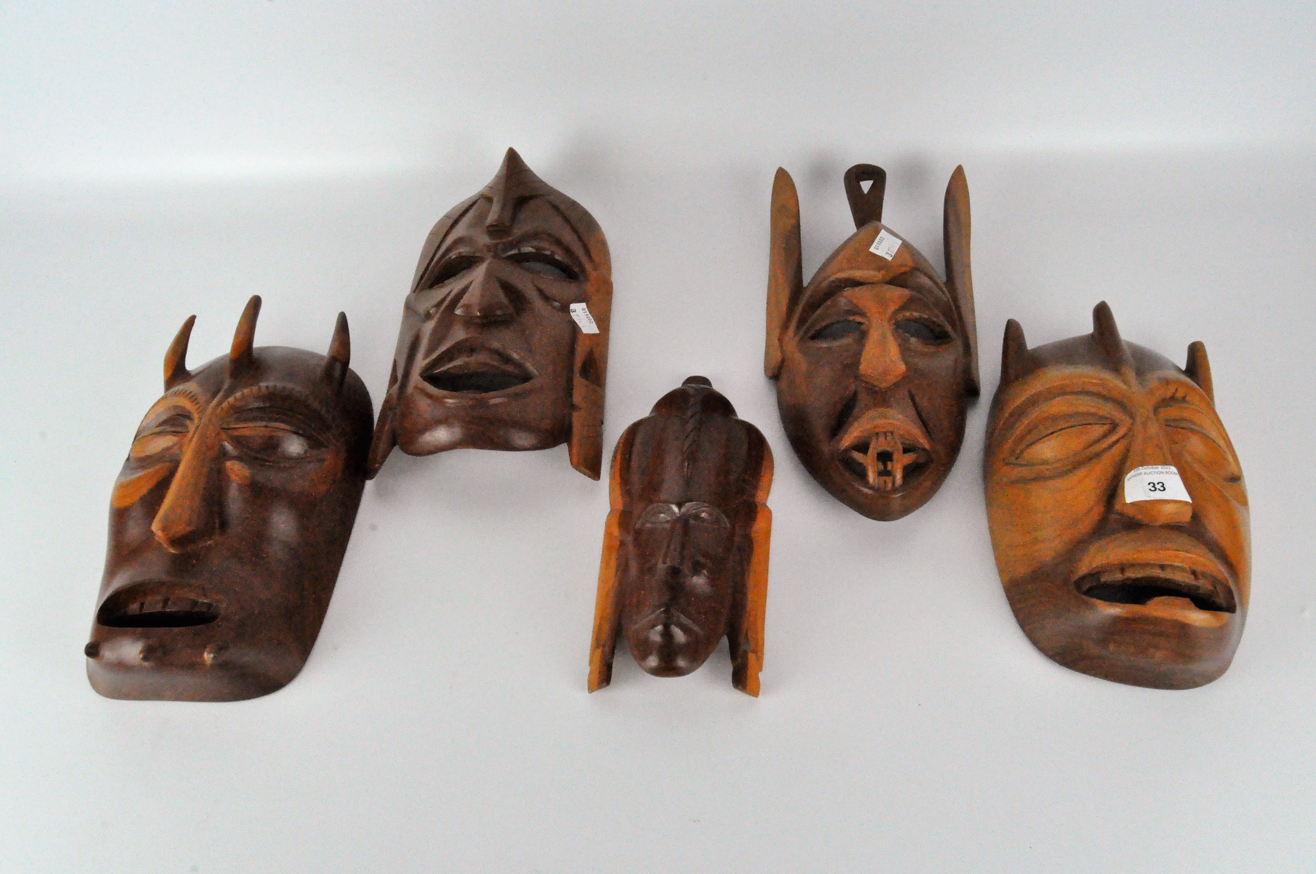 A collection of 1940's carved wooden masks, of assorted designs and sizes,