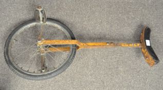 A vintage unicycle, painted metal frame with attached saddle,