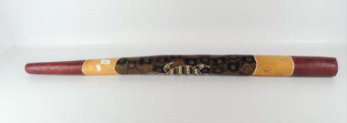 A didgeridoo, with applied red, yellow and orange dot detailing of a turtle,