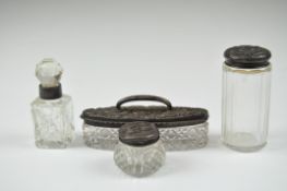 A group of four Edwardian glass dressing table bottles with silver lids,