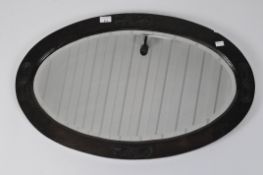 A stained wood bevelled edge mirror, the frame carved with four recessed leaf cartouches,