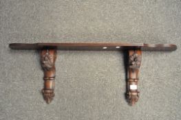 A 20th century rosewood wall shelf, the supports carved with flowers and foliage,