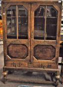 An Edwardian display cabinet with half glazed doors and carved details.