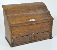 A vintage oak stationery box with shaped sloping lid, with two small hinged doors below,