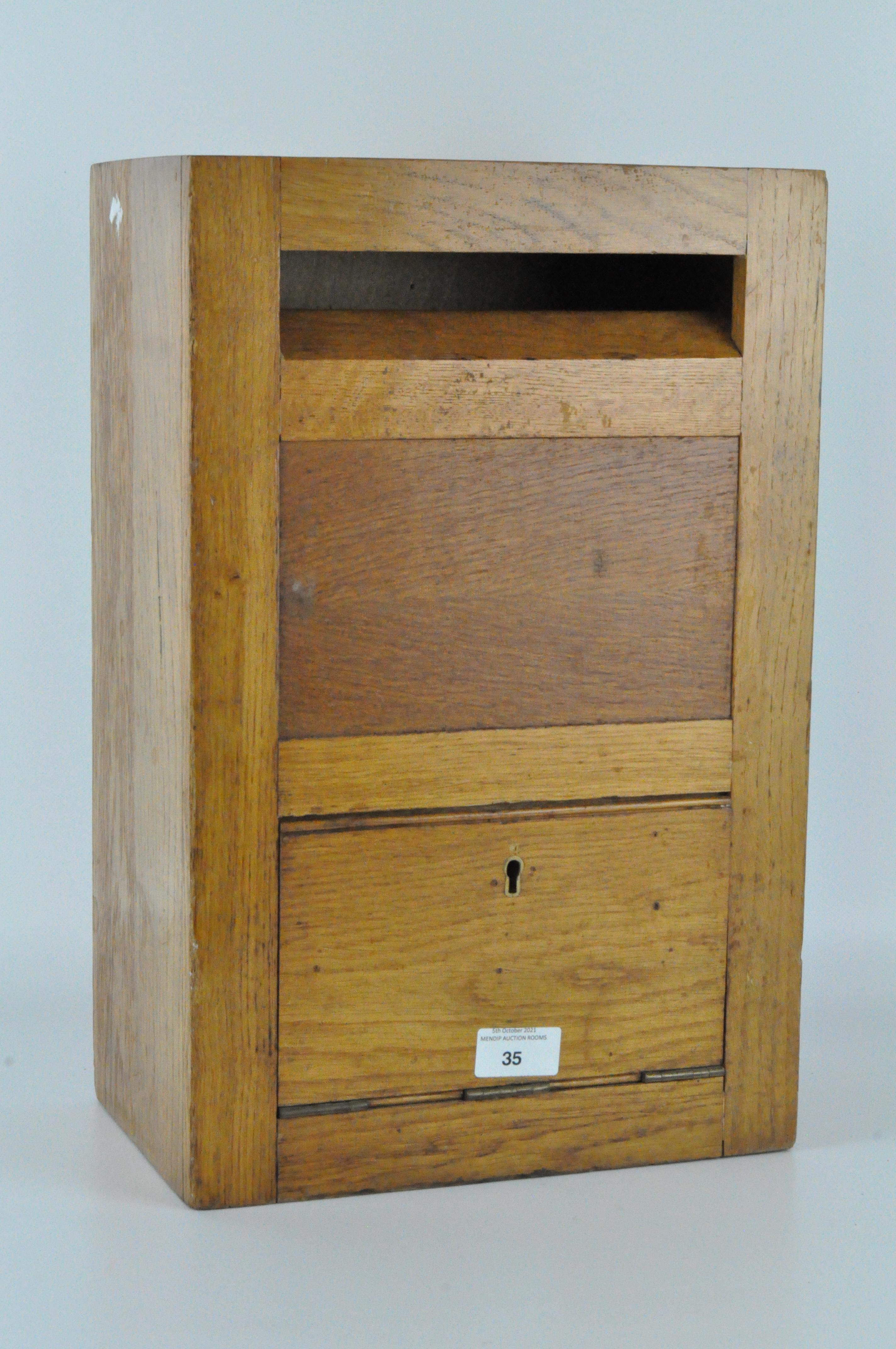 A vintage 20th century golden oak letter box with military notation to reverse,