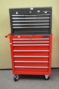 A red metal tool storage unit, with handle to one side, raised on wheels,