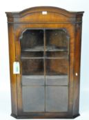 An early 20th century mahogany glass front corner cabinet with three scalloped shelves,