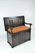 A dark stained oak hallway storage bench with raised carved details,