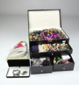 A jewellery box containing a large selection of costume jewellery, including necklaces,