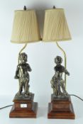 A pair of 20th century bronzed lamps, featuring a cherub holding a shell,