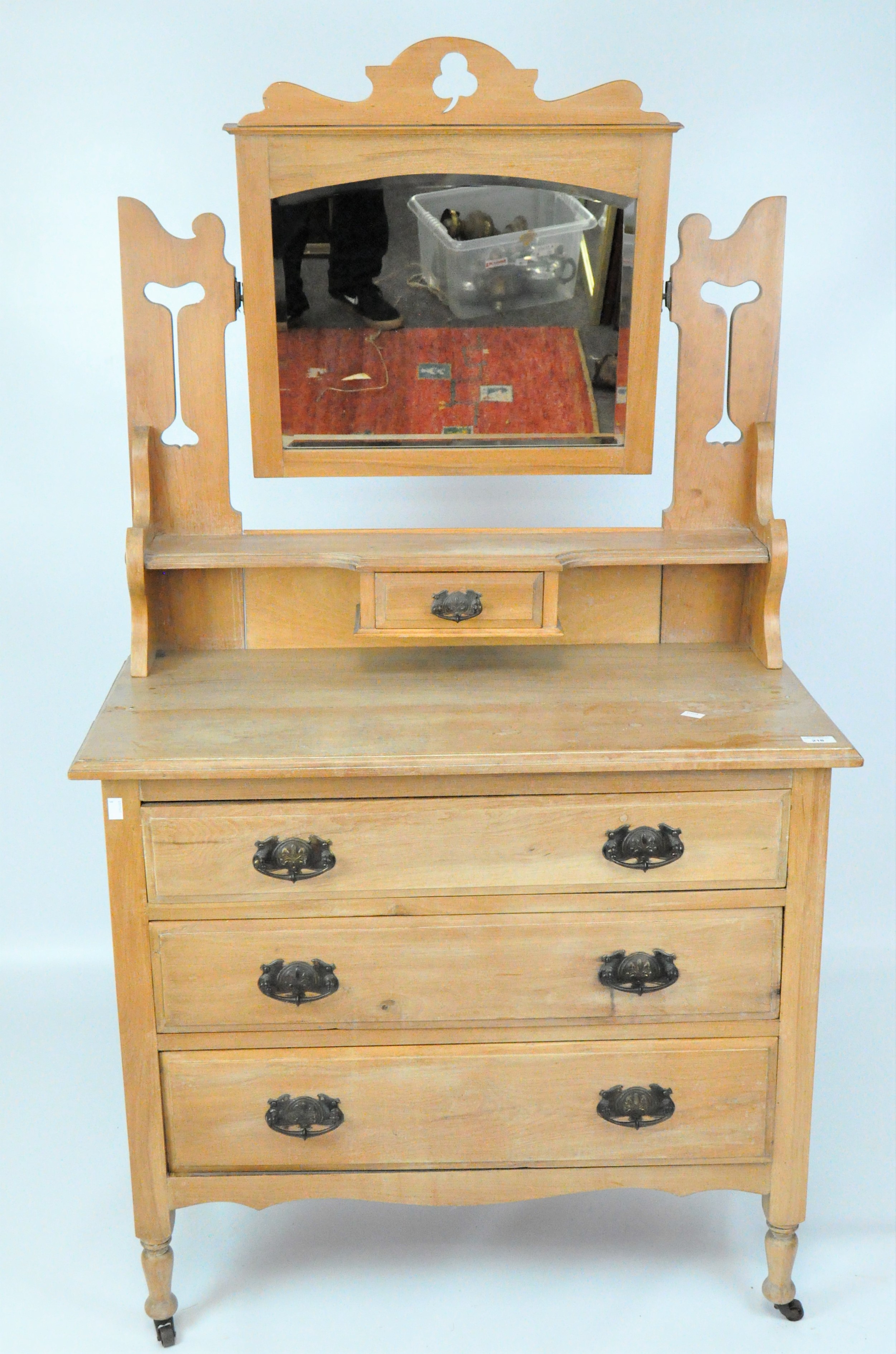 A Victorian pine dressing table with swing mirror suspended between pierced supports,