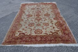A 20th century Persian style rug, woven with deer among scrolling foliage in cream, peach, blue,