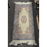 A small Chinese rug, 20th century, woven with flowers on ivory cream ground,