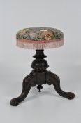 An adjustable Victorian piano stool on tripod support, with floral upholstery,