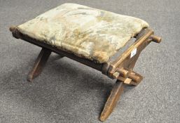 An early 20th century oak framed stool, X frame supports, with upholstered top.