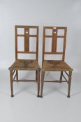 A pair of early 20th century chairs with a geometric metal inlay pattern to the back, rush seats,