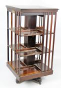 A large Edwardian mahogany revolving bookcase on a cross support and casters,