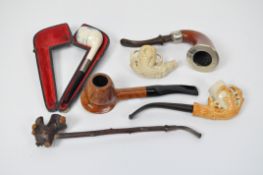 A collection of six smoking pipes, two with wooden frames, one formed from gnarled twigs,