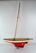 A wooden 20th century pond yacht, painted in white and red with metal rudder, missing sails,