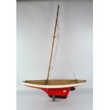 A wooden 20th century pond yacht, painted in white and red with metal rudder, missing sails,