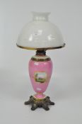 A pink porcelain vase form lamp decorated with landscape vignettes and gilt details,