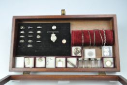 A tabletop display case, glazed, containing a selection of silver jewellery and other items,