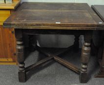 A 1920s oak draw leaf dining table, with cross stretchers, raised on turned baluster supports,