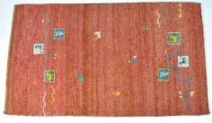 An Indian red ground rug with animals and geometric pattern, in primary colours,