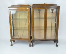 Two Art Deco display cabinets, each top edge carved with flowers and scrolls,