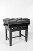 A modern black adjustable piano stool with padded black leather seat