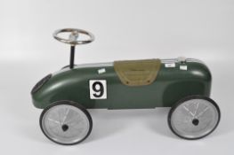 A vintage-style child's push along racing car in green with white tripes and number 9,